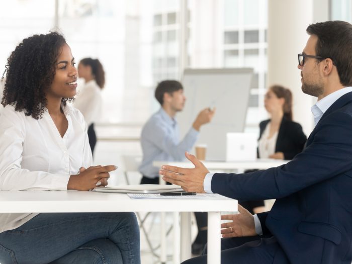 Diverse businesswoman businessman sitting at table in shared room discuss project, client and executive manager negotiating, boss interviewing new job candidate. Teamwork, collaboration or hr concept